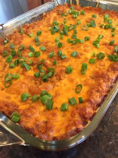 a casserole dish with cheese and green onions on it sitting on a counter