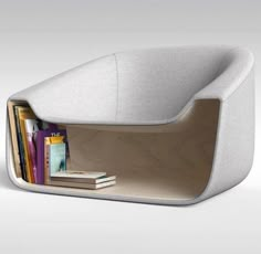 a white chair with books and magazines in it's back pocket, as well as a book shelf