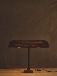 a table lamp sitting on top of a wooden table next to a brown cloth covered wall