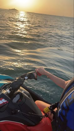 a woman riding on the back of a jet ski while holding onto something in her hand