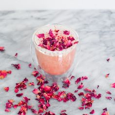 a glass filled with pink flowers on top of a table