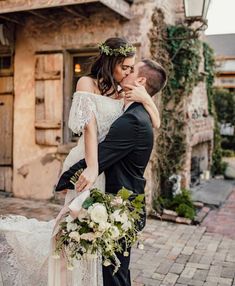 a bride and groom embracing each other in front of an old building with ivy on it