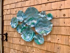 a blue and green wall hanging on the side of a wooden building next to a door