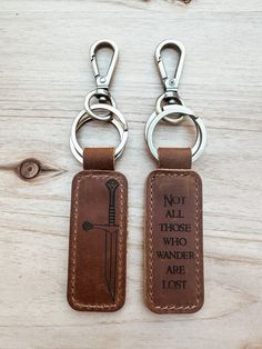 two leather keychains with the words not all those who wander are lost on them