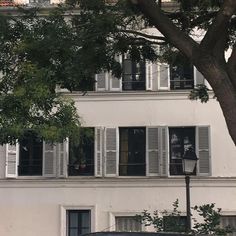 an old car parked in front of a tall white building with shutters on the windows