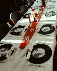 a long table is set with black and white plates, silverware, and red napkins