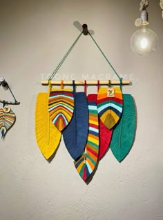 three colorful umbrellas hanging on a wall next to a light bulb and lamp fixture