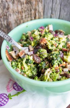 a green bowl filled with broccoli and other food on top of a table