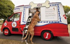 two dogs standing in front of a food truck with a dog bone on it's side