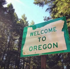 a welcome to oregon sign in front of some trees and blue sky with white clouds