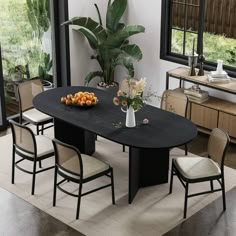 a dining room table with chairs and fruit on the table in front of large windows