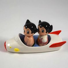 two figurines are sitting in a toy boat