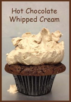 a chocolate cupcake with whipped cream on top and the words hot chocolate whipped cream above it