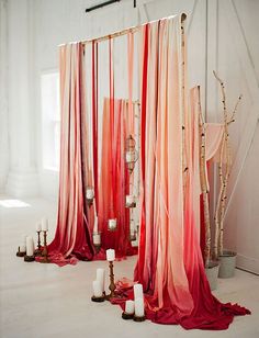 an arrangement of candles and draping in front of a white barn door with red curtains