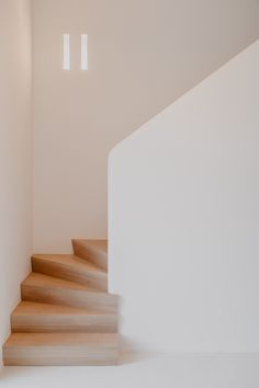 an empty white room with wooden steps leading up to the second floor