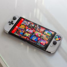 a nintendo wii game controller sitting on top of a white table next to a cell phone