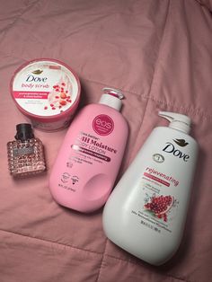 A selection of pomegranate and raspberry-scented body care items, including body lotion, body scrub, and perfume on a pink bedspread. Raspberry Body Wash, Raspberry Body Care, Berry Scented Shower Routine, Pomegranate Body Care, Pomegranate Body Wash, Shower Hygiene, Skin Care Routine Order, Fruit Scent