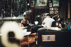 two people sitting at a table with papers and laptops in an old fashioned room