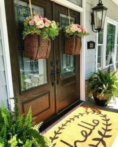 two baskets with flowers are hanging on the front door