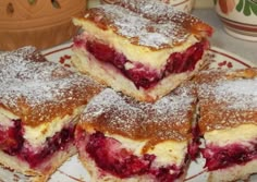 four pieces of cake on a plate with powdered sugar and cranberry toppings