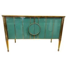 a green cabinet with gold trim and a circular handle on the front, against a white background