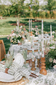 the table is set with candles and place settings for an outdoor dinner party or celebration