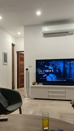 a flat screen tv sitting on top of a wooden table in front of a wall mounted air conditioner