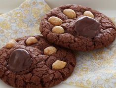 two chocolate cookies with peanut butter on top and a glass of milk next to it