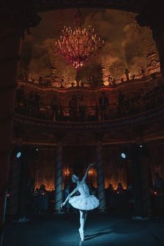 a ballerina is dancing in front of a chandelier