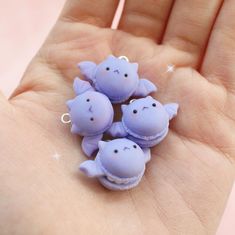 three little purple figurines sitting on top of someone's hand in the palm