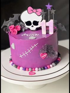 a birthday cake decorated with pink and purple icing, skulls, stars and decorations