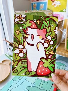 a person holding up a card with a cat on it's face and flowers in the background