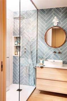 a bathroom with blue and white tiles on the wall, wooden cabinets and a round mirror