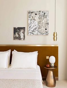 a bed with white sheets and pillows next to a painting on the wall above it