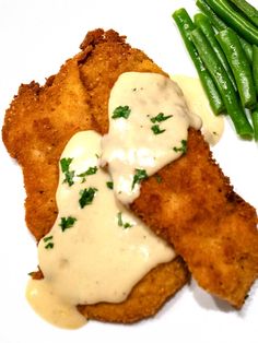 fried fish and green beans are served on a white plate with gravy sauce