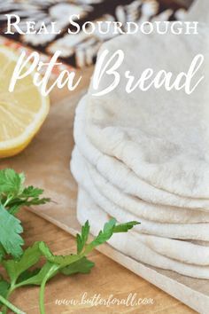 a pile of pita bread sitting on top of a cutting board next to lemons and parsley