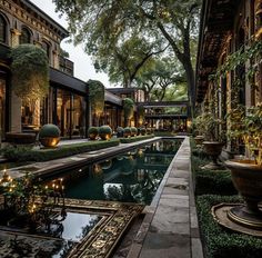 an outdoor pool surrounded by greenery and potted plants with lights on the sides