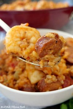 a spoonful of sausage and rice casserole is being held over the bowl