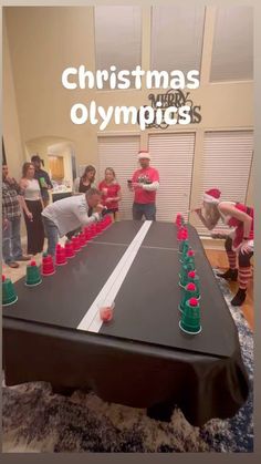 a group of people standing around a table with cups on it and the words christmas olympics in front of them