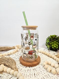 a glass with a straw in it sitting on a table next to beads and plants