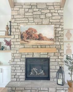 An eye-catching natural stone fireplace steals the spotlight in this living room. It is accessorized with a wooden mantel, a golden-frame artwork of autumnal trees, and a black-accented farmhouse-styled candle holder. Flanking it are wooden floating shelves and artwork...   Image: pleasantlybuilt