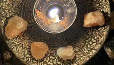 a candle is lit in a bowl with rocks around it