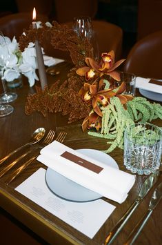 the table is set with silverware, flowers and candles for dinner guests to enjoy