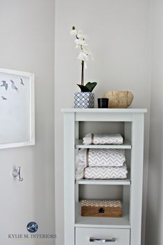 a white shelf with towels and a vase on top