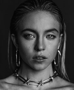 a woman with large hoop earrings and piercings on her neck is staring at the camera