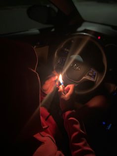 a person holding a lighter in their hand while sitting in the driver's seat