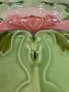 a pink flower sitting on top of a green plate with swirls and bubbles around it