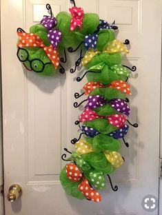 a wreath made out of green mesh and polka dots with lady bug decorations hanging on the front door