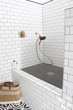 a white tiled bathroom with a shower head and hand held shower faucet in the corner