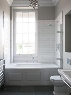 a white bath tub sitting under a window next to a toilet